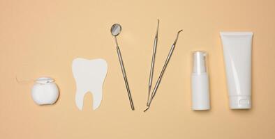 dentaire miroir, tube de dentifrice et dentaire soie sur une marron Contexte photo