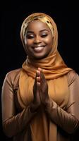 africain femme portant écharpe est prier et souriant sur noir Contexte photo