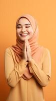 sud-est asiatique femme portant écharpe est prier et souriant sur Orange Contexte photo