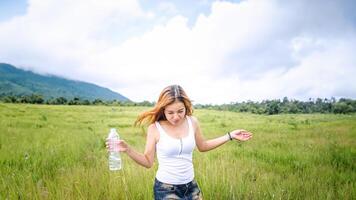 les femmes asiatiques voyagent se détendent pendant les vacances. boire de l'eau sur un pâturage vert. photo