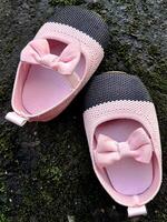 mignonne peu bébé des chaussures rose et noir Couleur sur plâtre et mousse les plantes Contexte photo