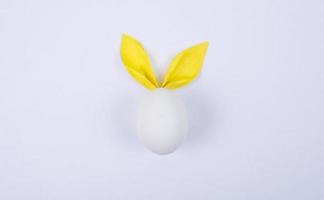 œuf avec des oreilles en papier en forme de lapin de Pâques. joyeux pâques concept carte postaer fond photo