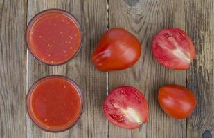 verres avec du jus de tomates rouges mûres sur table en bois