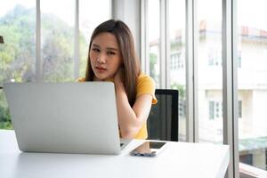 magnifique Jeune asiatique femme d'affaires, épaules et retour douleur pendant travail longue temps sur lieu de travail. corps muscles rigide problème après longue journée travail et surmené. Bureau syndrome et soins de santé concept. photo