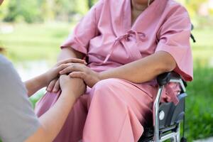 asiatique prudent soignant ou infirmière prise se soucier de le patient dans une fauteuil roulant. concept de une content retraite avec se soucier de une soignant et des économies et Sénior santé assurance, encourager le patient photo