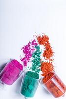 coloré Holi poudre dans une Plastique conteneurs sur blanc Contexte. photo