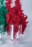 rouge et vert Holi poudre dans une mesure tasse sur blanc Contexte. photo