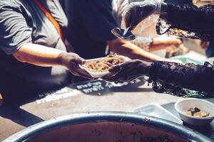 bénévoles remise délicieux nourriture à le sans abri pauvres . concept de faim problème photo