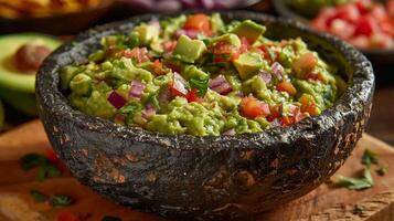 Frais guacamole dans rustique bol avec mûr avocat, tomate, chaux, et coriandre photo