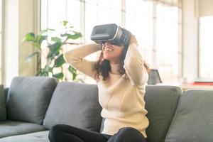 femme latine à l'aide d'un casque de réalité virtuelle sur canapé photo
