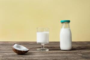 une verre et une bouteille avec noix de coco Lait sur une en bois table photo