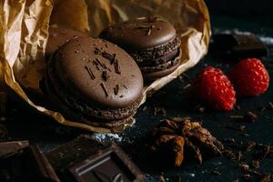 Chocolat macarons avec framboises sur une foncé Contexte photo