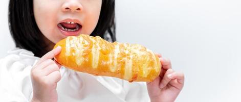 fermer. mains d'enfant tenant du pain long jaune. derrière le pain, des enfants ouvrent la bouche pour croquer dans une pâtisserie sucrée. photo