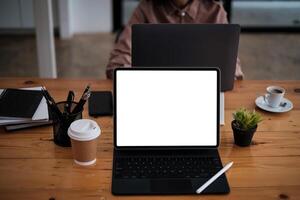 maquette image de noir tablette avec clavier et Vide blanc écran avec affaires équipe travail à Contexte sur en bois bureau. photo