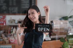 à sa café boutique, souriant petit affaires propriétaire tournant autour ouvert magasin retour à ouvert le magasin après COVID-19 [feminine. photo