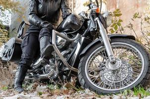 Fille en veste de motard en cuir et bottes noires sur une moto chopper photo