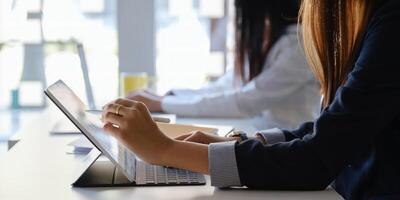 Jeune Créatif designer en portant style et main montrer du doigt à tablette tandis que séance à Accueil Bureau avec sa équipe. travail de Accueil concept. photo