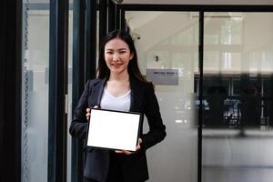 affaires femme en portant numérique tablette avec blanc écran à Bureau photo