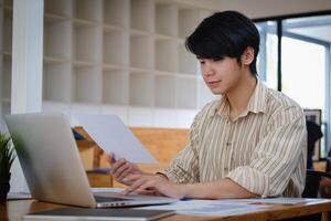 asiatique étudiant concentrer apprentissage en ligne cours et en train de regarder Didacticiel via portable ordinateur à vivant pièce dans maison,. en ligne classe pièce concept. photo