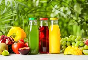 bouteilles de jus sains, fruits et légumes sur table à l'extérieur, gros plan photo