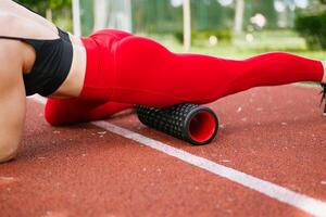 thème sport et réhabilitation des sports médicament. magnifique fort mince caucasien femme athlète les usages massage rouleau à faire des exercices à retirer douleur, étendue et massage muscles. photo