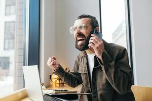 en colère caucasien Masculin pigiste dans café ayant querelle pendant mobile téléphone conversation discuter problèmes avec en ligne affaires projet, nerveux à la recherche homme est parlant sur le téléphone. photo