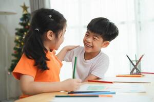 deux les enfants sont séance à une table avec crayons de couleur et coloration livres. elles ou ils sont souriant et en riant, profiter leur temps ensemble. concept de bonheur et relation amicale entre le deux les enfants photo