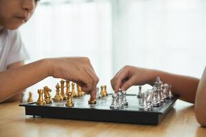 deux les enfants en jouant une Jeu de échecs. un de le les enfants est portant une blanc chemise. le Jeu est étant joué sur une noir et blanc planche photo