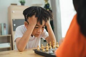 une garçon est en jouant échecs avec un autre personne. il est à la recherche à le planche avec une triste expression photo