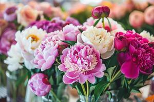 beaucoup différent pivoines dans une verre des vases dans une moderne fleur magasin. photo