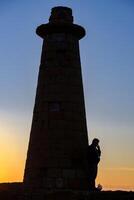 une homme permanent et fumeur par le phare de kyrenia port à le bleu heure dans Chypre photo