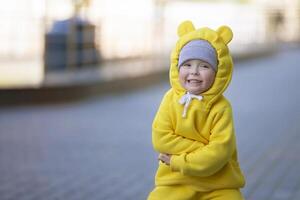 marrant peu fille dans une chaud Jaune costume avec oreilles sur une marcher. photo