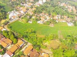 oiseau œil vue de village parmi riz des champs dans bandung ville, Indonésie. paysage de les terres agricoles avec riz terrasse agricole cultures dans campagne. agricole champ. au-dessus de. coup de une drone en volant photo