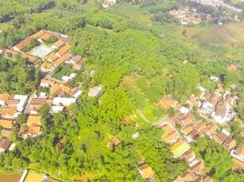 oiseau œil vue de village parmi riz des champs dans bandung ville, Indonésie. paysage de les terres agricoles avec riz terrasse agricole cultures dans campagne. agricole champ. au-dessus de. coup de une drone en volant photo