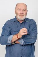 portrait de un attrayant aux cheveux gris homme dans une denim chemise isolé sur une gris Contexte. barbu grand-père de le européen taper. photo