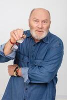 portrait de un indigné aux cheveux gris homme dans une denim chemise sur une blanc Contexte. barbu grand-père de le européen taper. photo