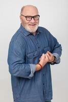 portrait de un attrayant aux cheveux gris homme dans une denim chemise montrant force isolé sur une blanc Contexte. barbu grand-père de le européen type est de bonne humeur et heureux. photo