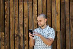 homme envoyer des SMS sur téléphone intelligent contre en bois mur photo