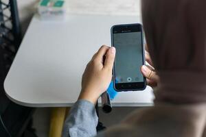 femme avec hijab en train de préparer le enregistrement mobile téléphone à faire produire contenu photo