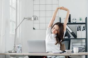 femme d'affaires prend une moment à étendue et se détendre à sa bureau, dans une brillant et aéré Bureau espace. photo