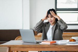 Bureau ouvrier exprime choc avec mains sur tête tandis que regarder à une portable filtrer, une scène de inattendu nouvelles ou Erreur à travail. photo