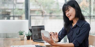 de bonne humeur Jeune femme avec un appareil dentaire en utilisant calculatrice tandis que séance à une café avec une portable. photo