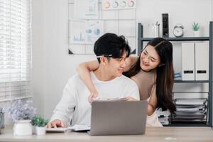 aimant couple étroitement révision des plans sur une tablette dans leur organisé Accueil bureau, partage une moment de affection. photo