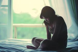 asiatique fille sentiment triste et solitaire dans le chambre en dessous de faible lumière photo