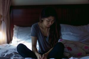 asiatique fille sentiment triste et solitaire dans le chambre en dessous de faible lumière photo