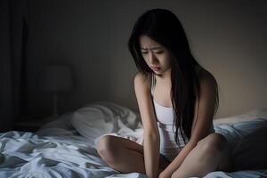 asiatique fille sentiment triste et solitaire dans le chambre en dessous de faible lumière photo