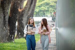 Université étudiant fille copains avec apprentissage livre Université tandis que en marchant dans Campus photo
