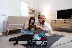 Jeune asiatique femme emballage vêtements à le valise. préparation pour le heure d'été vacances. deux femmes sont Planification une voyage et portion à préparer bagage à Voyage photo