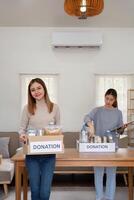 don et deux femme bénévole asiatique de content emballage nourriture dans boîte à maison. charité photo