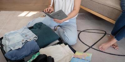 Jeune femme emballage dans valise tandis que séance sur le sol et en train de préparer pour sa vacances photo